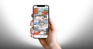 A hand holding a phone with several social posts about commercial listings on it.